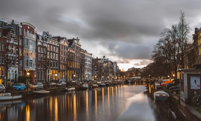 Amsterdamse gracht bij schemering met verlichte gebouwen